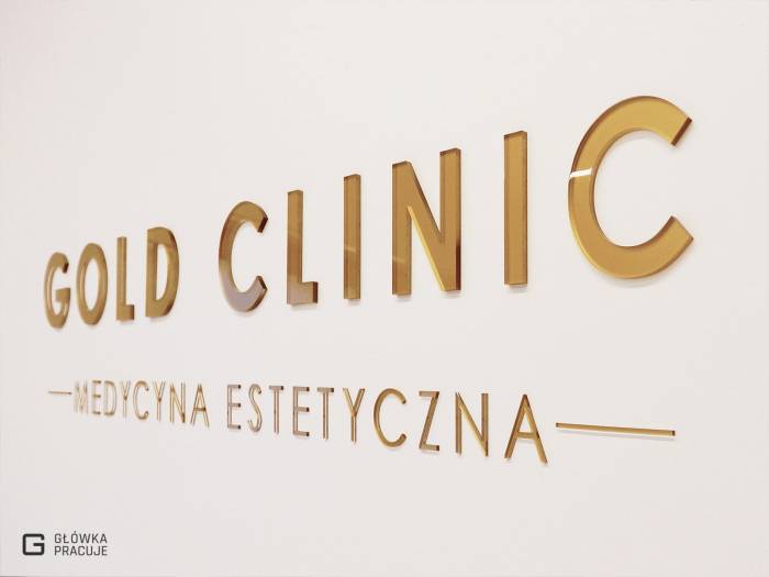 Główka pracuje pl Gold Clinic logotyp z plexi bezbarwnej podklejonej złotą folią, gabinet