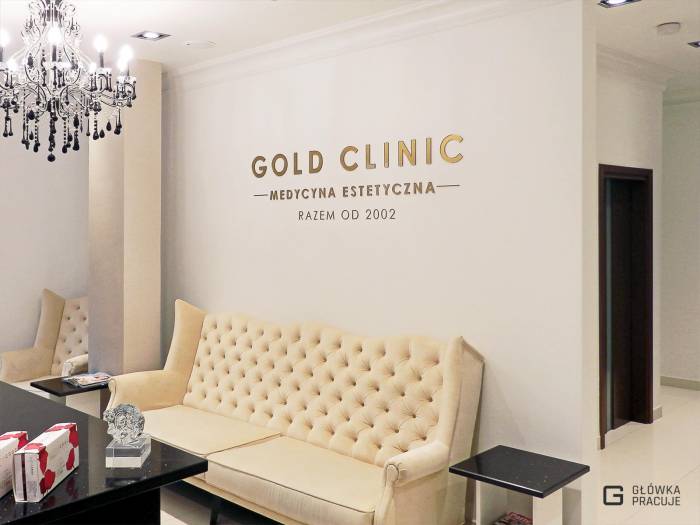 Główka pracuje pl Gold Clinic logotyp z plexi bezbarwnej podklejonej złotą folią, recepcja